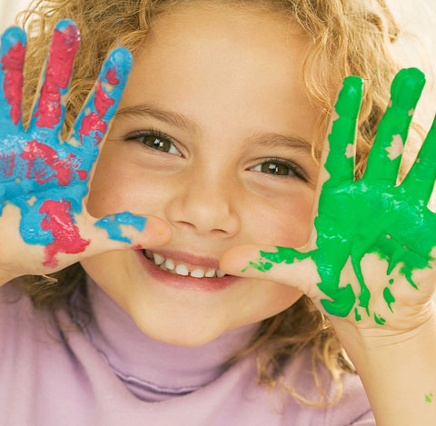 Young child with colorful painted hands showing creative expression